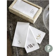 three personalized towels in a wooden box on the ground next to a glass bowl