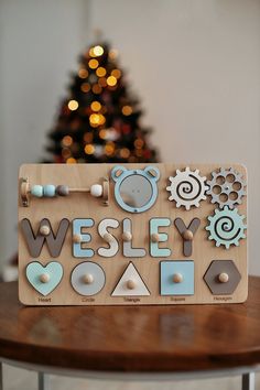 a wooden sign sitting on top of a table next to a christmas tree in the background