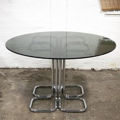 a glass table with metal legs on concrete floor