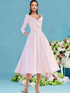 a woman in a pink dress standing next to a flowery wall with flowers on it