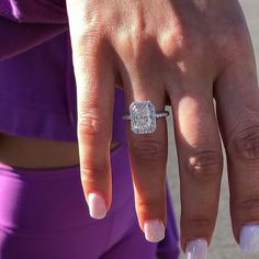 a close up of a person's hand with a diamond ring on her finger