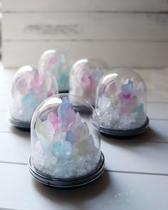 four snow globes sitting on top of a white wooden table next to each other