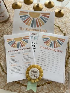 two baby shower games on a table with wine glasses and gold bells in the background