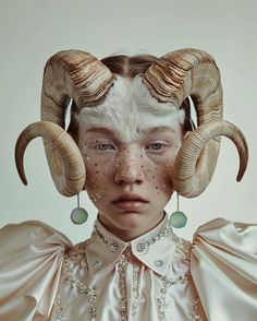 a woman with white makeup and horns on her head