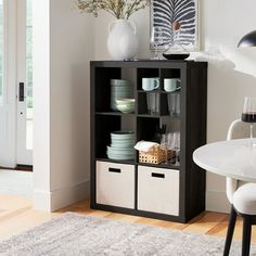 a black and white bookcase with baskets on it in the corner of a room