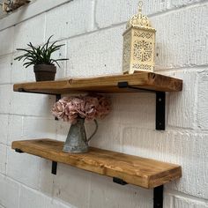 two wooden shelves with metal brackets and flowers on them against a white brick wall,