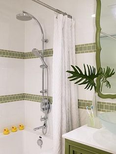 a bathroom with green and white tile, shower head, sink, mirror and bathtub