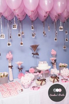 a table topped with lots of pink and white balloons next to pictures on the wall