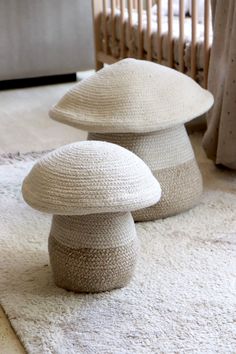 two knitted mushroom stools sitting on top of a rug in front of a crib