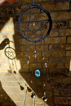 a hand is holding up a black and white wind chime with crystal balls hanging from it