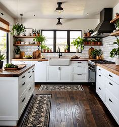 a kitchen filled with lots of white cabinets and counter tops covered in potted plants