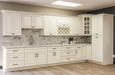 an empty kitchen with white cabinets and marble counter tops