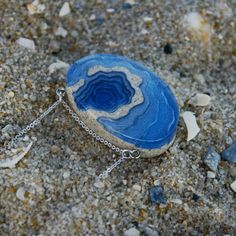 A ring-shaped reef, island, or chain of islands formed of coral The Atoll pendant has been carefully handmade from bonded beach sand, ultramarine or aqua blue resin and metal pigments with a high-gloss polished finish. Two eye screws connect the piece to a fine cable link chain. All metal parts are rhodium plated. Each purchase from BoldB's Aqua Collection will help provide one year of safe water to one person in need through BoldB's support of Water.org, an international nonprofit organisation. Unique Blue Jewelry For The Beach, Blue Sterling Silver Necklace For Beach, Blue Pendant Jewelry For Beach, Ocean-inspired Blue Pendant Jewelry, Blue Sterling Silver Necklaces For Beach, Sterling Silver Blue Necklaces For Beach, Oval Blue Agate Jewelry, Blue Oval Agate Jewelry, Blue Gemstone Jewelry For The Beach