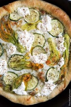 a pizza topped with cucumbers and cheese on top of a black pan covered in sauce