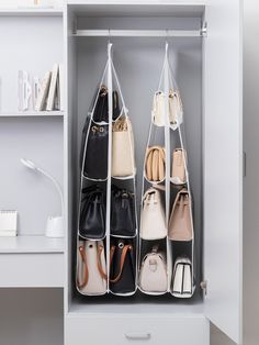 an organized closet with handbags and purses hanging on the wall, in front of a desk