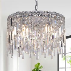 a crystal chandelier hanging from the ceiling in a room with white walls and windows