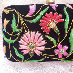 Turn heads wearing this colorful floral embroidered black velvet evening clutch bag. Be bright and bold! This exclusive design is expertly hand embroidered by master zardozi artisans. Each petal and leaf is outlined with glittery metallic gold threads and embellished with genuine semi precious stones, including garnets, turquoise, carnelian and onyx. Shop sustainably - own a handbag of exceptional quality that you will keep forever and pass down to the next generation. View more exclusive embroi Traditional Black Clutch With Handwork, Traditional Black Clutch For Festivals, Traditional Black Clutch, Embroidered Multicolor Clutch For Evening, Embroidered Evening Clutch For Festivals, Evening Clutch With Embroidery For Festivals, Evening Embroidered Clutch For Festivals, Traditional Multicolor Embroidered Clutch For Evening, Traditional Multicolor Embroidery Clutch For Evening