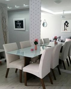 a glass dining table surrounded by white chairs