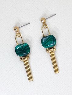 These earrings feature beautiful green malachite stones at their centre.  The smooth, oval semi precious stones show vibrant green hues and natural banding patterns contrasting with the golden fine, narrow fringe of brass that dangles below.  The simplicity of the arched design further contributes to the elegant, minimalistic aesthetic that compliments and allows the uniqueness of the natural stone to shine.  A brass ball stud with stainless steel post holds the design at the top.  Approximate measurements- 5.5cms long 1.5 cms wide  All Set Theory jewellery comes with care instructions and a polishing pad to keep your jewels looking shiny and fabulous! ✨ Modern Green Metal Earrings, Modern Green Malachite Jewelry, Green Minimalist Brass Earrings, Minimalist Green Brass Earrings, Modern Green Brass Jewelry, Modern Green Earrings For May Birthstone, Modern Green May Birthstone Earrings, Set Theory, Arched Design