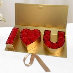 a box with roses in it and the word u is made out of gold foil