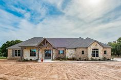 a large brick house sitting on top of a dirt field