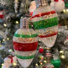 two ornaments hanging from a christmas tree in front of a decorated christmas tree with lights