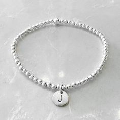 A dainty 3mm pure sterling silver bracelet with tiny personalised sterling silver initial charm. Choose your letter- either the wearers' initial or someone close to her heart- to make it even more special.  Our bracelets are made of the highest quality pure US sterling silver beads, and are lovingly hand-strung into your special bracelet by our family, just for you.  Bracelet length should be approximately 1.5cm larger than wrist circumference. All orders come in gift box with soft suede jewelle Sterling Silver Charm Bracelet With Initials In Silver, Elegant Silver Name Bracelet With Letter Beads, Silver Dainty Bracelet With Initials, Dainty Silver Bracelets With Initials, Dainty Silver Bracelet With Initials, Elegant Hand Stamped Silver Name Bracelet, Silver Dainty Initials Name Bracelet, Personalized Silver Charm Bracelet With Initials, Minimalist Silver Charm Bracelet With Initials