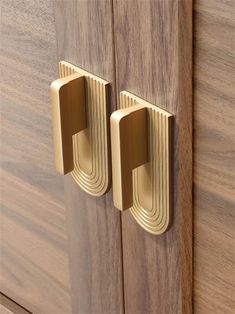 two brass handles on wooden cabinets with wood grained doors and drawers in the background