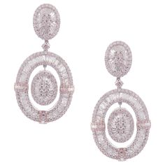 These modern oval baguette earrings are crafted in 18-karat white gold, weighing approximately 14.65 total carats of SI-V Quality white diamond. French Clip backing. Beautiful rose gold accent. Our Ballroom Collection feature earrings for those with bold/classy aesthetics and elegant tastes. 346 Round Diamonds = 7.84 ct 235 Baguette Diamonds = 6.81 ct