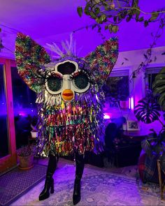 a woman standing in front of a purple light wearing a costume made out of tinsel