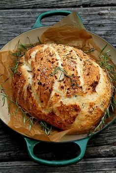 a loaf of bread sitting in a pan on top of a wooden table next to a pair of scissors