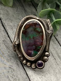 This ring is from my Twigs and Succulents Line. The focal of this piece is a Winton Boulder Opal from the Winton Mine in Australia. This stone has lots of fire and color. Tube set in the designs is a lovely faceted Amethyst. The setting has a sterling silver cast twig surrounding the opal. The setting is all hand fabricated from .999 fine silver and sterling. The ring is a US size 7 Unique Oval Amethyst Ring With Gemstone Accents, Unique Silver Opal Ring With Gemstone Accents, Unique Oval Amethyst Cabochon Ring, Unique Amethyst Multi-stone Rings, Unique Multi-stone Gemstones For Healing, Unique Opal Ring For Collectors, Unique Opal Ring With Gemstone Accents, Unique Multi-stone Amethyst Jewelry, Unique Multi-stone Amethyst Ring In Sterling Silver