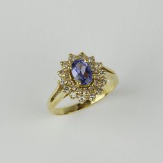 a yellow gold ring with an oval blue sapphire surrounded by small white diamonds