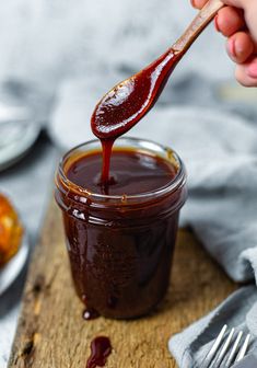 a spoon full of ketchup on top of a wooden cutting board