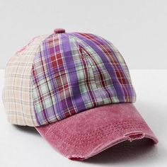 a plaid hat is shown on a white surface with a pink visor in the foreground