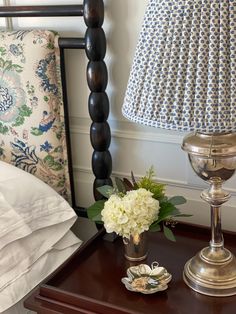 a nightstand with a lamp and flowers on it