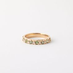 a yellow gold band with green stones on the side and white diamonds in the middle