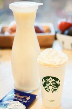 there is a cup of starbucks coffee next to a card and a vase on the table