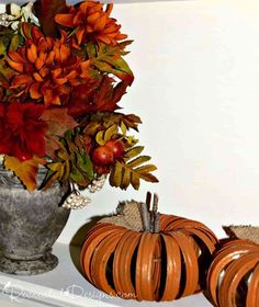 a vase filled with flowers and pumpkins sitting on top of a white shelf next to other fall decorations