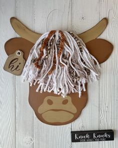 an animal head made out of wood with white dreadlocks on it's ears