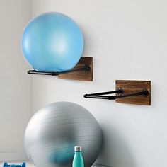 there are two ball holders on the wall and one is holding an exercise ball, while the other holds a water bottle