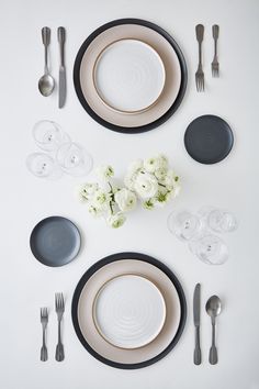 the table is set with black and white plates, silverware, and flower centerpieces