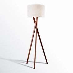 a wooden tripod floor lamp with a white shade on it's top and bottom