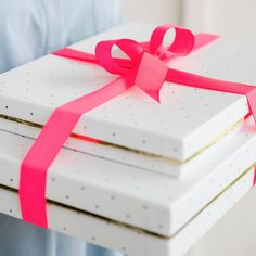 a stack of white boxes with pink ribbon