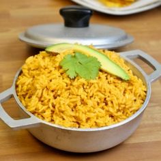 a pot filled with yellow rice and topped with an avocado on the side