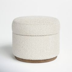 a white ottoman sitting on top of a wooden base