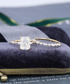 an engagement ring and wedding band sitting on top of a pillow