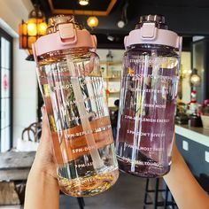 two people holding up water bottles with labels on them