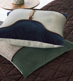 three pillows stacked on top of each other with a decorative vase in the back ground