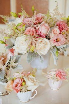 a vase filled with pink and white flowers next to two mugs on a table